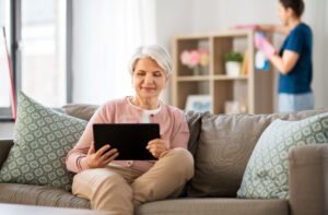 old woman with tablet pc and housekeeper at home
